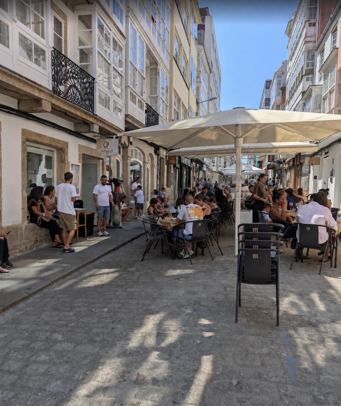 Terraza de O Pincho en la calle peatonal de Ferrol con clientes bajo sombrillas
